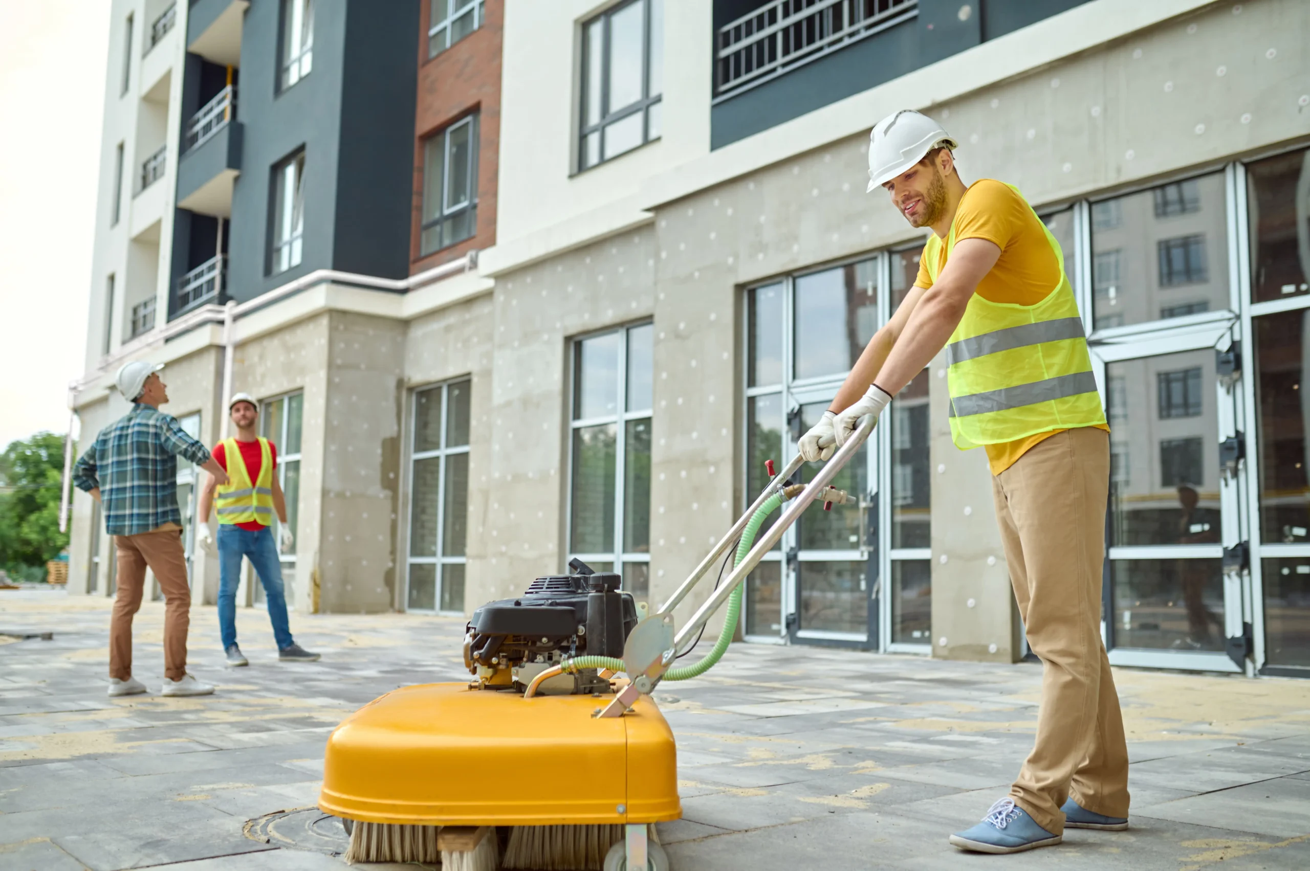 worker-cleaning-construction-site-and-two-men-near-2023-11-27-05-15-45-utc